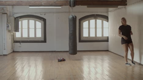 Long-shot-of-young-woman-running-with-high-knees-in-boxing-room